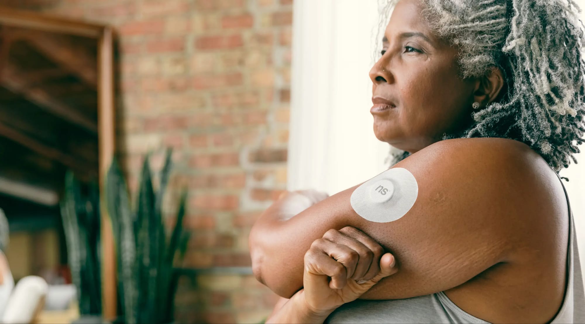 A woman wearing a continuous glucose monitor on her upper arm
